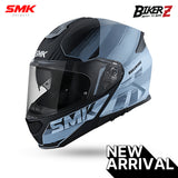 A black and gray SMK brand flip-up motorcycle helmet with a full face visor, featuring high-visibility graphics and a 'NEW ARRIVAL' label.